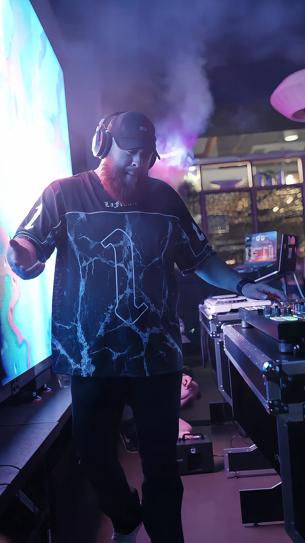 G at the decks in a number 1 jersey, fog and an LED wall behind him